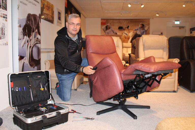 Ein Arbeiter kniet neben einem Stuhl für die Polsterreparatur.