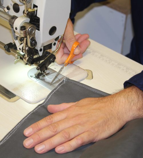 Ein Mann näht mit Nadel und Faden Stoff für die Polstermöbelreparatur.